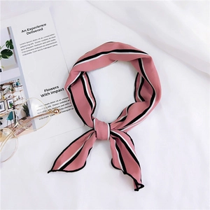 Pink silk scarf with black white striped edges and golden glasses on white fabric