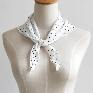 Elegant white polka dot silk scarf tied on a mannequin neck for a stylish layered look