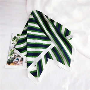 Close-up of green and navy striped silk scarf with hand-painted artistic brushstroke texture