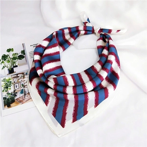 Detail of red, blue and white striped silk scarf tied in a knot on a white fabric background