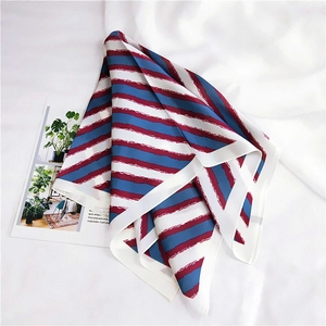 Detail of red and navy blue striped silk scarf with white borders on textile background