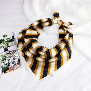 Detailed close-up of a striped silk scarf with elegant yellow and navy blue stripes