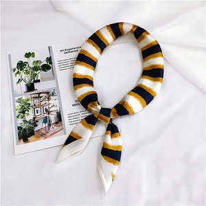 Detail view of navy blue and gold striped silk scarf tied in a bow on white fabric