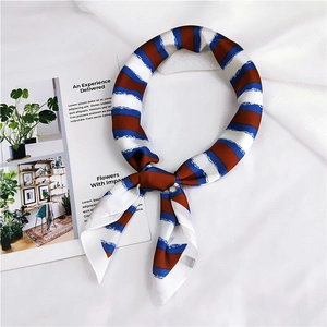 Detail of red and blue striped silk scarf folded on a white fabric with a magazine