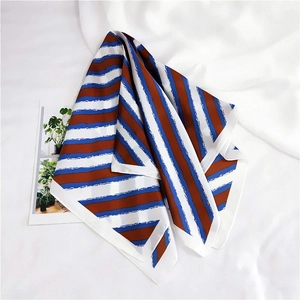Detail of silk-like square scarf with brown and blue diagonal stripes on white cloth