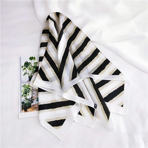 Close-up of black, gold, and white striped silk scarf texture on pleated background