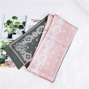 Detailed flat lay of pink and dark green paisley satin scarves on a magazine
