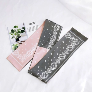 Close-up of pink and dark grey paisley printed ribbon scarves on white fabric background