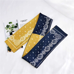 Detail of a dual-sided paisley silk scarf featuring mustard yellow and navy blue colors