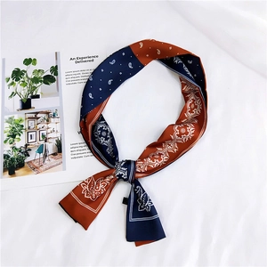 Close-up of paisley pattern silk ribbon scarf in navy and rust red with satin finish