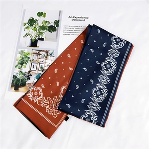 Detail of navy and caramel paisley satin neck scarves on a minimalist white background