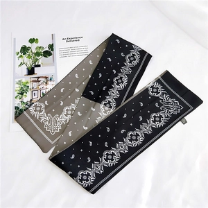 Detail of a two-tone paisley and polka dot silk twilly scarf over a white fabric background