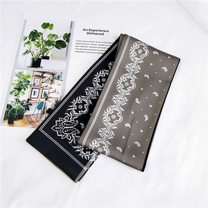 Flat lay detail of paisley pattern twilly scarves in black and taupe on white background