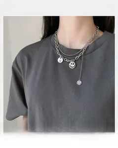 Dettaglio della collana multistrato in titanio argento con faccina e ciondolo inciso
