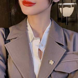 Broche fleur élégante avec texture coquillage et bord doré sur un blazer de costume gris