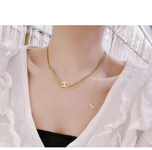 Collana a doppio strato in oro con pendenti a lettera H su una catena a maglia spessa