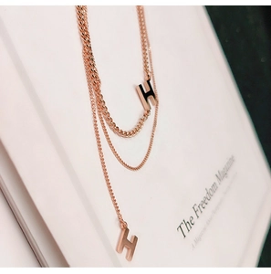 Collana a doppio strato in oro rosa con pendenti a lettera H dal design minimalista