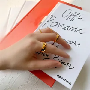 Polished gold minimalist titanium rings in various widths worn by hand model