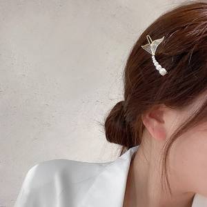 Elegant gold fishtail hair clip with white faux pearls worn by a model in hair