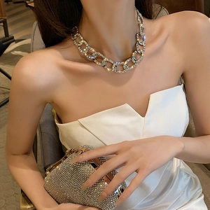 Gros plan sur le collier à chaîne cubaine serti de strass brillants et pochette assortie