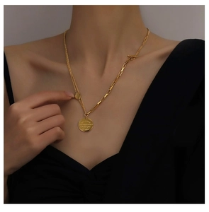 Detail of gold asymmetric layered necklace with OT clasp and coin pendant on model