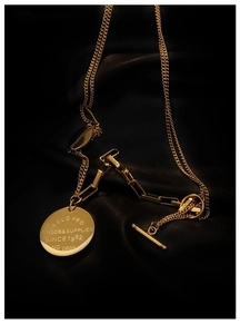 Detail of gold toggle clasp necklace with engraved round pendant on black leather