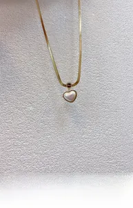Detailed close-up of golden snake chain with heart mother of pearl and Love pendant