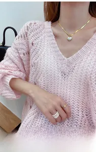 Close-up of gold snake bone chain necklace with heart pendant on pink knit sweater