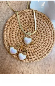 Macro detail of gold herringbone necklace with iridescent heart pendant and Love engraving