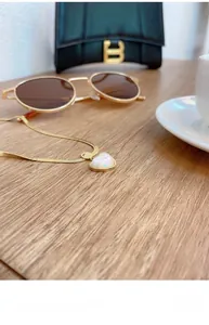 Detail of a gold snake chain necklace with a pearlescent heart pendant on wooden surface