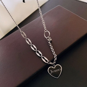 Macro detail of asymmetric silver chain and black heart pendant with Forever engraving