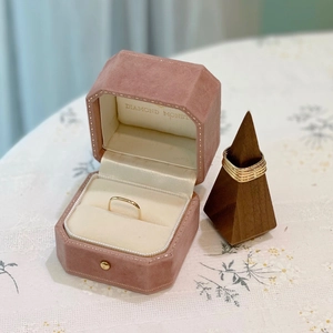 Ensemble de bagues dorées minimalistes dans un écrin en velours rose sur tissu fleuri