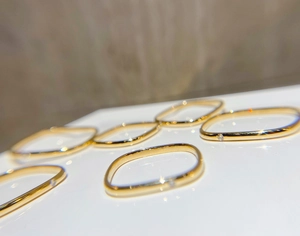 Détail de bagues géométriques dorées avec zircon et anneau fin au style épuré