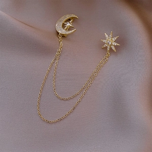 Close-up of elegant gold moon and star brooch with zircon stones and double chains