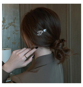 Close-up of golden leaf hair clip with pavé zircons and a pearl decoration