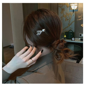 Detailed close-up of leaf hair clip with marquise zircons and white pearl on hair