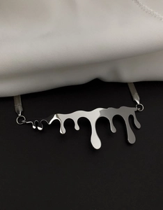 Macro shot of liquid metal pendant on flat snake chain against black and white silk