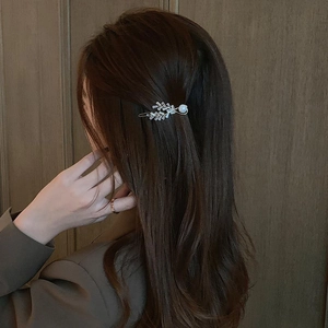 Elegant gold leaf barrette with sparkling zircon and pearl shown on brown hair