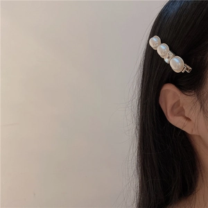 Dettaglio di un fermaglio per capelli con perle e cristalli su capelli neri e oro