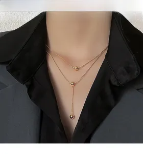 Detail of layered gold titanium steel necklace with polished beads on a female model