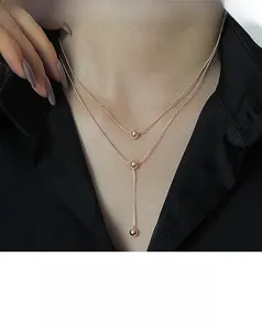 Close-up of golden double-layered titanium necklace with beads and Y-shaped tassel pendant