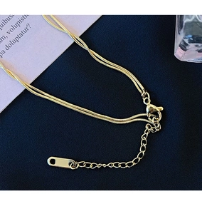 Macro detail of gold double-layered snake chain necklace with lobster clasp and extender