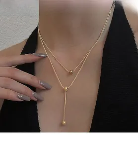 Detail of layered gold titanium necklace with minimalist beads on elegant snake chain