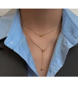 Close-up of elegant double-layered gold bead necklaces styled with a blue shirt