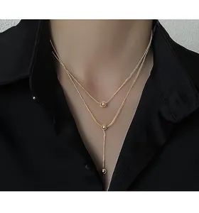 Detail of gold double-layered snake chain necklace with round beads on black shirt