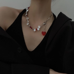 Baroque pearl necklace with heart pendant and red beads worn on a model
