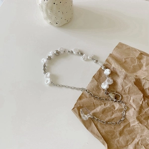Detail of baroque pearl necklace with heart pendant and silver metallic chain link