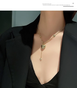 Dettaglio della collana con pendente a cuore dorato e stella su blazer nero