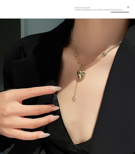 Dettaglio di una collana dorata con ciondolo a cuore e stella indossata da una modella