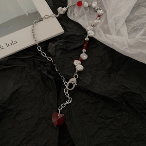 Baroque pearl necklace with red heart crystal pendant on black textured background